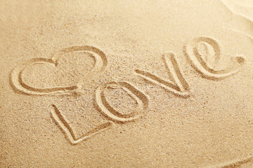 Love handwritten on a beach sand