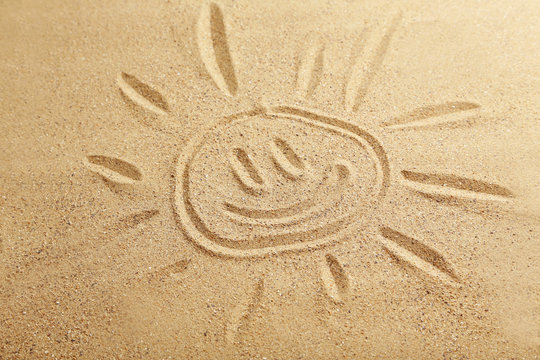 Drawing sun on beach sand