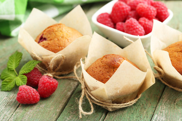 Fresh cupcakes with raspberries on green wooden background