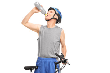 Fototapeta na wymiar Senior biker standing behind his bicycle and drinking water