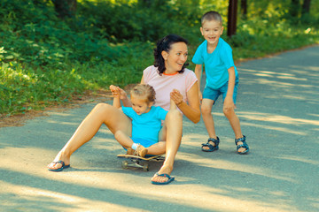 Fototapeta na wymiar Family fun with skateboard. Little kids ride on a skateboard mom