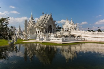 The famous white temple in the Chiang Rai province reflecting in the water