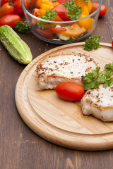 Fried pork steak with vegetables and parsley on a wooden board
