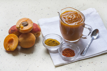 Apricot curry in a glass jar, spices and fresh apricots, selective focus