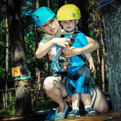 Mom and little son in the outfit have been climbing the trees. Mom and young son  in a special outfit studying climbing the trees