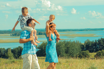 young beautiful family of four on the background of the open landscape