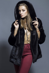 Sexy Beauty Girl with natural  Make up.  Fashion Blonde Portrait of a girl dressed in fur coat posing on a grey background.
