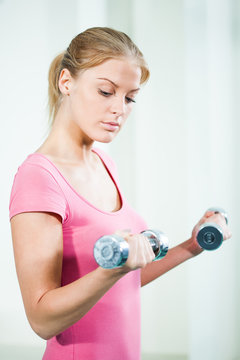 Woman exercising in gym, using weights