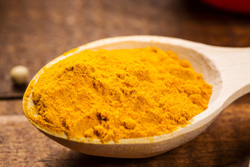Close up of measuring spoon in pile of organic turmeric (curcuma) powder