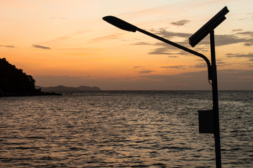 street light with solar panel against sea at sunset