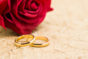 Wedding rings and artificial rose on brown background - Powered by Adobe