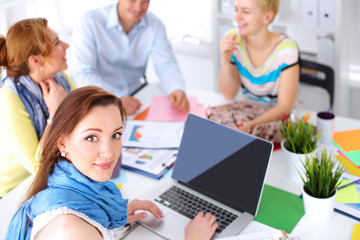 Portrait of attractive female  designer sitting on desk  in