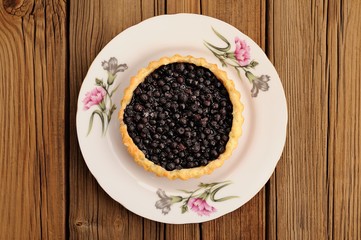 Homemade tart with whole wild blueberries in white plate with pi