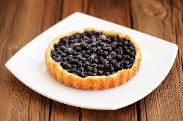 Homemade round tart with whole wild blueberries in square white