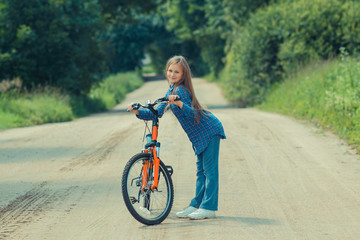 Teenager girl with bicycle in countryside outdoors