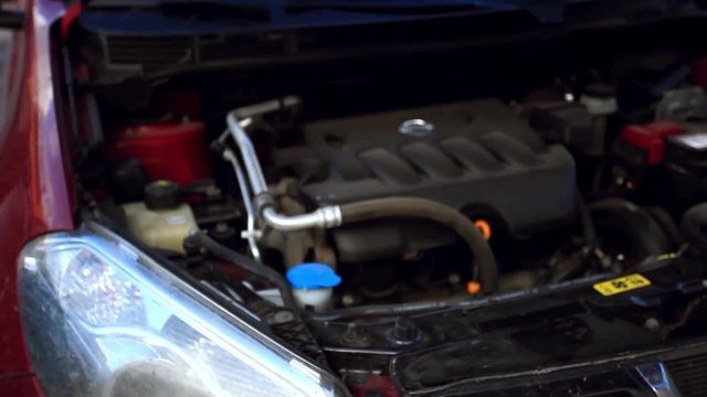 man opens the hood of a car and Filling windshield washer fluid