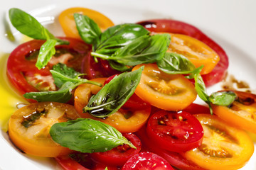 Vegetable salad of colorful tomatoes and basil with olive oil an