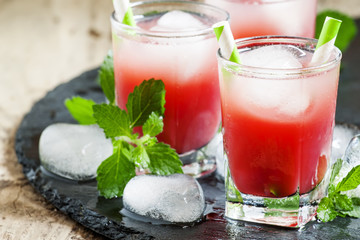 Cold red cocktail with ice and mint on a dark background, select