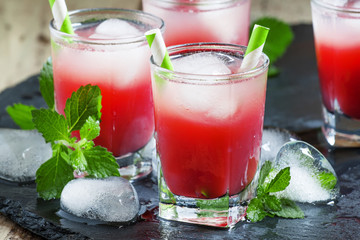 Cold red cocktail with ice and mint on a dark background, select