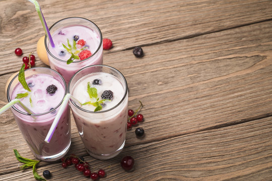 Three glasses of various fresh berries smoothies, with space for