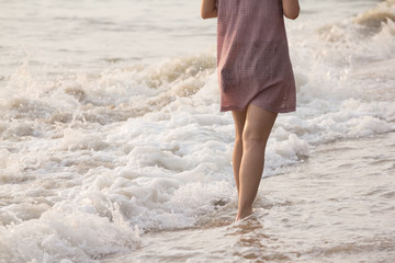 Girl walking on the beach with her bare foot.