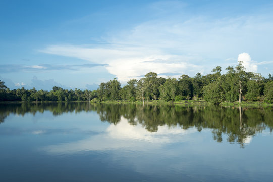 Scenic view of lake with lush tropical greenery reflecting under bright Asian sky in the moat at Angkor Wat, Cambodia