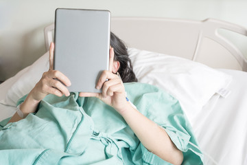 Mature female patient used tablet on bed in hospital