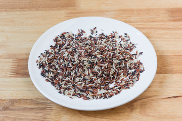 Rice brown  in a ceramic plate with wooden background.