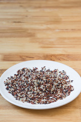 Rice brown  in a ceramic plate with wooden background.