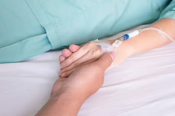 Close up of a husband touching hand of a wife patient in hospita