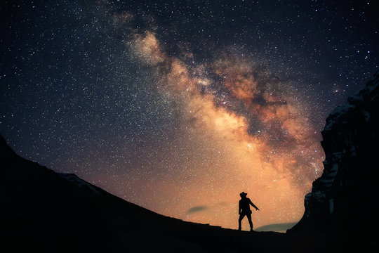Guardian of the Galaxy. A man is standing next to the Milky Way galaxy and the night sky full of stars. 