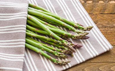 Fresh green asparagus on wooden background with linen cloth