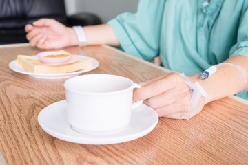 Mature female patient eating healthy breakfast in hospital.