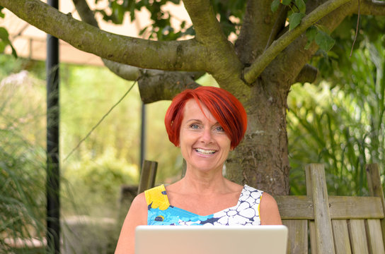 Frau mit ihrem Laptop unter einem Baum