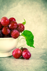 still life with red grapes in white  vintage cup