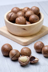 Macadamia in wooden bowl on white wooden table