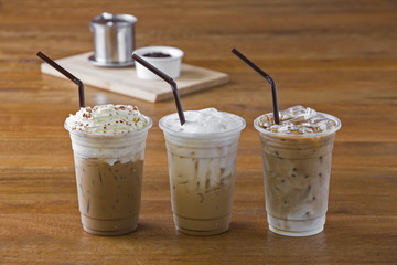 Ice coffee with whipped cream and coffee beans on wooden table.