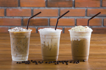 Ice coffee with whipped cream and coffee beans on wooden table.
