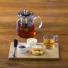 breakfast table with tea, teapot, cup of tea, jam, bread and hon
