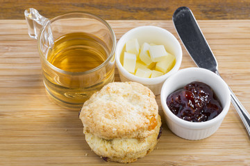 breakfast table with tea, teapot, cup of tea, jam, bread and hon