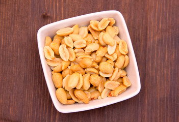 Salted nuts on bowl on wooden table top views