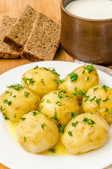 Traditional Ukrainian food boiled new potatoes with butter and dill on wooden table
