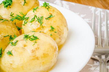 Traditional Ukrainian food boiled new potatoes with butter and dill on wooden table