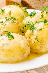 Traditional Ukrainian food boiled new potatoes with butter and dill on wooden table