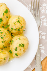 Traditional Ukrainian food boiled new potatoes with butter and dill on wooden table