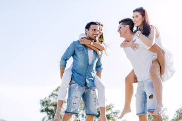 Group of young happy people carrying women on a sandy beach