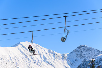 Fototapeta na wymiar Unidentified skiers on lift in beautiful winter scenery of Tatra Mountains, Slovakia