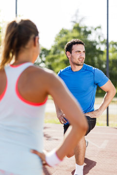 Young athletic man and woman stretching outdoors on a hot summer