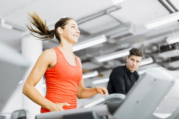 Fototapeta na wymiar Beautiful young woman running on a treadmill in gym