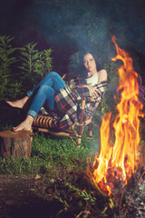 Pensive girl sitting near bonfire